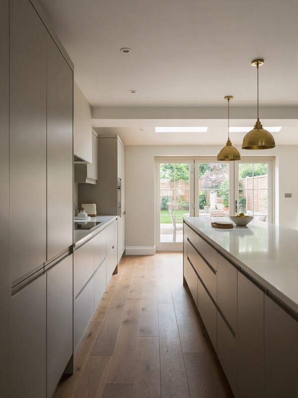 Warm grey handleless kitchen with island and brass pendants in Brentwood