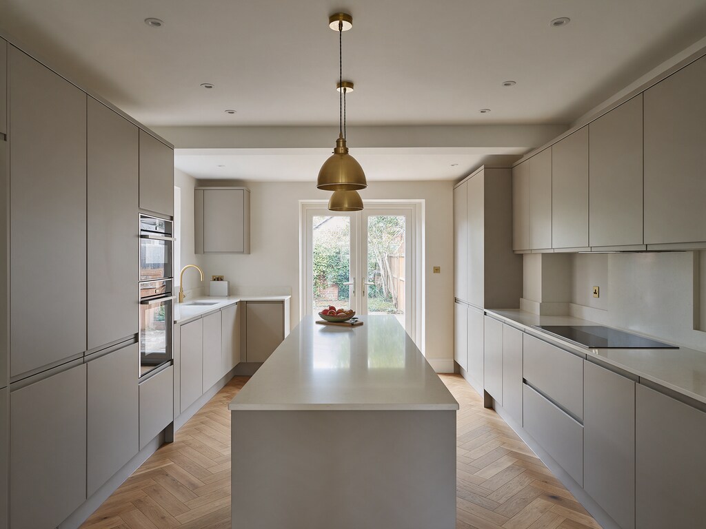 Finished handleless kitchen with long island and herringbone floor in Brentwood